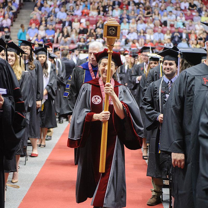 一位教授拿着仪式权杖进入毕业典礼